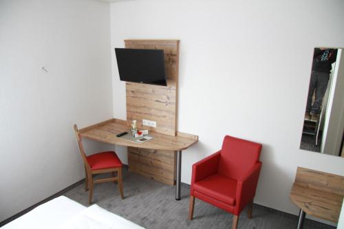 a small room with a table and a red chair at Hotel Lamm in Waiblingen
