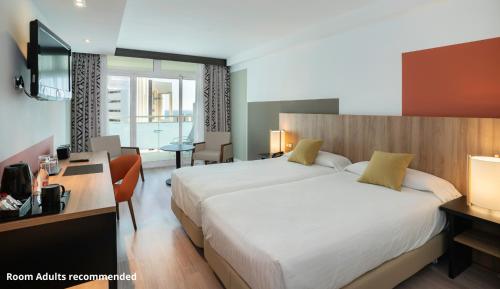 a hotel room with a large bed and a desk at Medplaya Hotel Flamingo Oasis in Benidorm