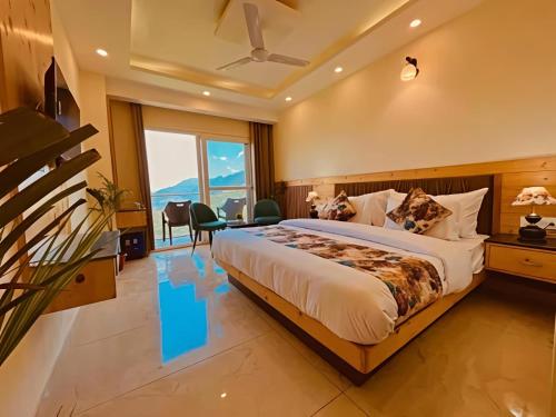 a bedroom with a large bed and a large window at The Pine Woods - A Four Star Luxury Resort In Mussoorie Near JW Marriott in Mussoorie