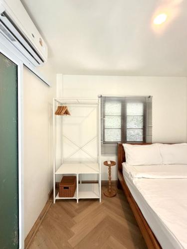 a white bedroom with a bed and a table at Simple Cozy House Coconut Lane in Hinkong