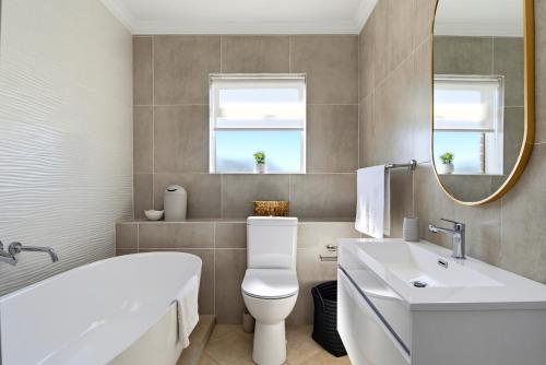 a bathroom with a tub and a toilet and a sink at Club 10 Management in Ballito