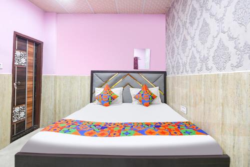 a bedroom with a large white bed with colorful pillows at FabHotel Mohini Palace in Vrindāvan