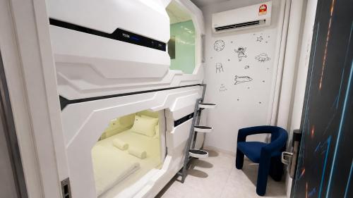 a small room with a bed and a blue chair at Space Hotel KL Sentral in Kuala Lumpur