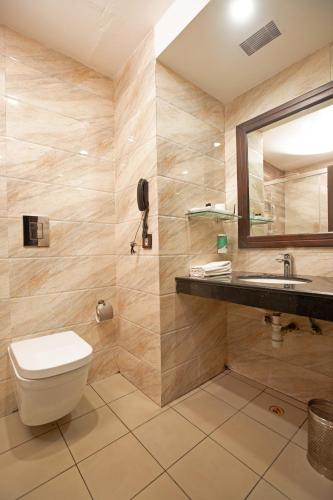 a bathroom with a toilet and a sink and a mirror at Hotel Atithi in Guwahati