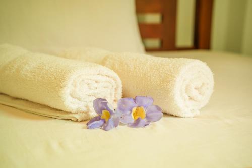 a pair of towels and purple flowers on a bed at Ocean villa in Hiriketiya