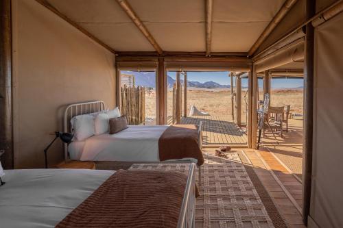 a bedroom with two beds and a view of the desert at Wolwedans Desert lodge in NamibRand