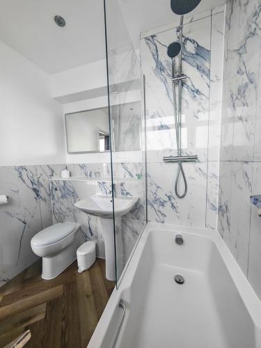 a bathroom with a tub and a toilet and a sink at The Hannafore Point Hotel in Looe