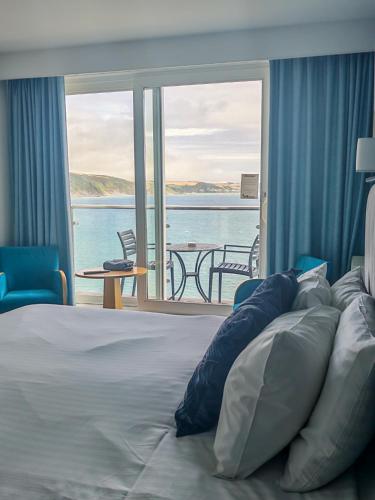 a bedroom with a bed with a view of the ocean at The Hannafore Point Hotel in Looe