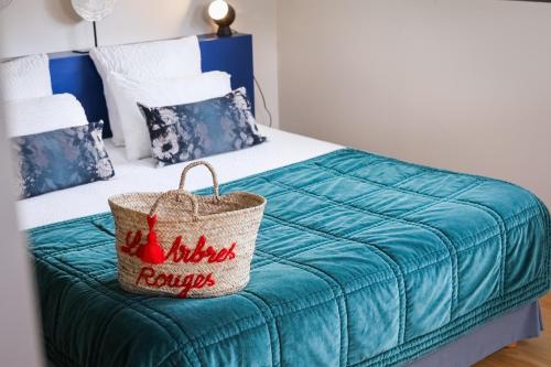 a bed with a blue blanket and a basket on it at Les Arbres Rouges in Sucé