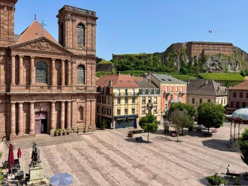 a large building with a church with a hill in the background at Hotel-Restaurant St-Christophe in Belfort