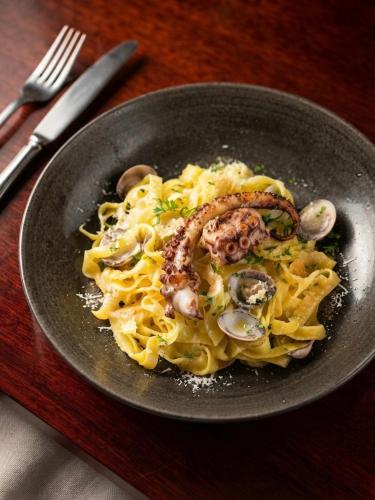 a plate of pasta with seafood and mushrooms on a table at Hotel Kalliohovi - ilmastoidut huoneet - in Rauma