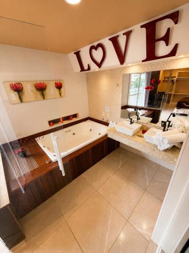 a large bathroom with a tub and a sink at Don Marcos Hotel com Pizzaria in Guarujá