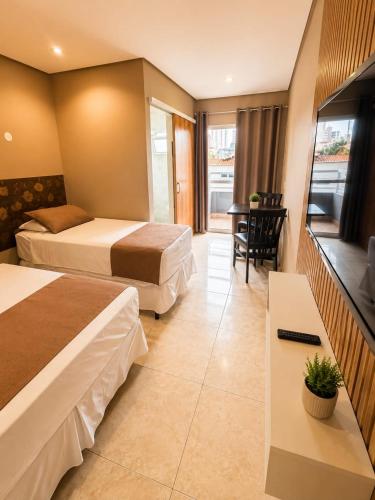 a hotel room with two beds and a television at Don Marcos Hotel com Pizzaria in Guarujá