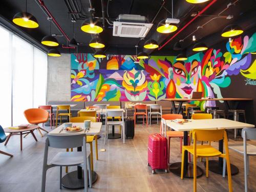 a restaurant with tables and chairs and a colorful wall at ibis Budget Bogota Marly in Bogotá