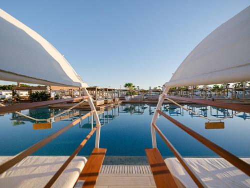 a pool with chairs and umbrellas in a resort at Lago Resort Menorca - Casas del Lago Adults Only in Cala en Bosc