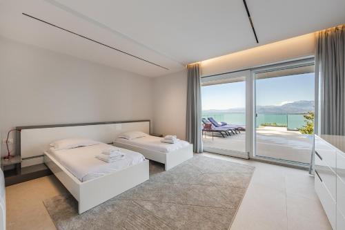 a bedroom with two beds and a balcony at Sunrise - The Twin Villa by PikHost in Shirokë