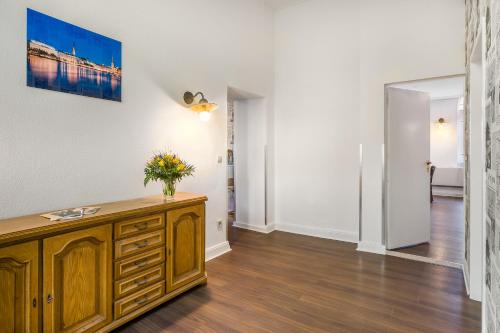 a living room with a wooden cabinet with a vase of flowers on it at Signature Hotel Astoria in Hamburg