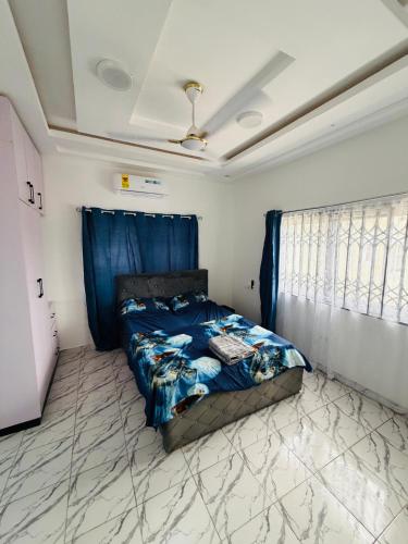 a bedroom with a bed with a blue comforter at Pebview 2 Bed Apartment in Kpone