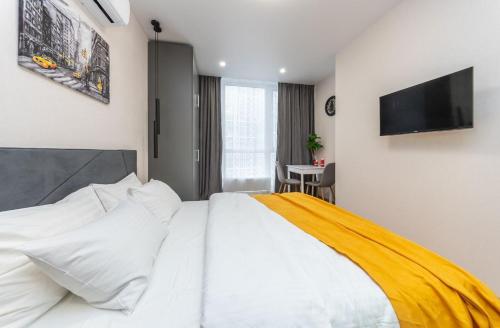 a bedroom with a white bed with a television on the wall at Видові Апарти на Озеро поруч з метро Позняки Харківська Ревуцького in Kyiv