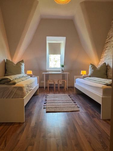 a bedroom with two beds and a table and a window at Zimmervermietung Villa Meuselwitz in Meuselwitz