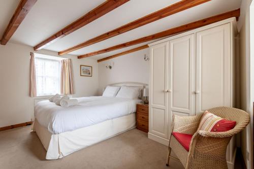 a bedroom with a white bed and a chair at Mariners Cottage - Elie in Elie