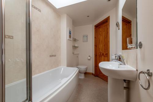 a bathroom with a tub and a sink and a toilet at Mariners Cottage - Elie in Elie
