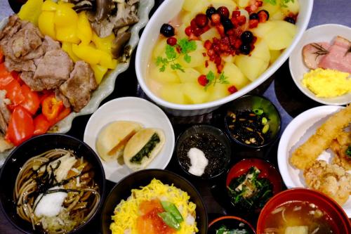 a table topped with bowls of different types of food at Dormy Inn Nagano in Nagano