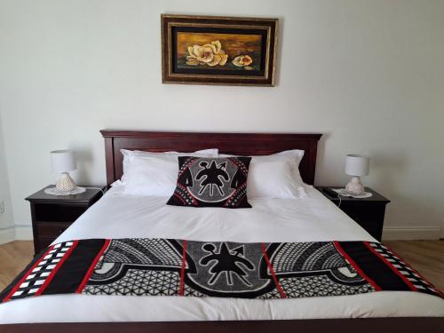 a bedroom with a bed with two tables and two lamps at Martha's Guesthouse in Gqeberha