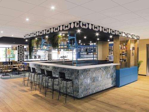 a bar in a restaurant with stools around it at Ibis Styles Miramas in Miramas