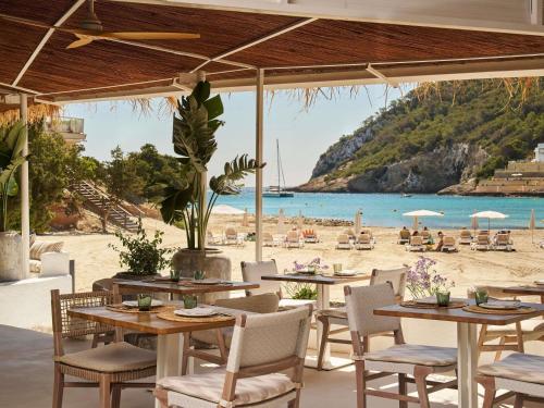 a restaurant with tables and chairs and a beach at Hyde Ibiza Beach Resort by Accor in Cala Llonga