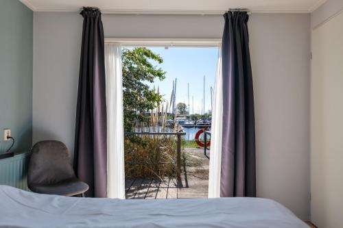 a bedroom with a window with a bed and a chair at Luwte aan het Lauwersmeer, Friesland in Anjum