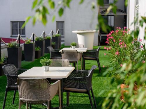 a row of tables and chairs on a lawn with plants at Mercure Szekesfehervar Magyar Kiraly in Székesfehérvár