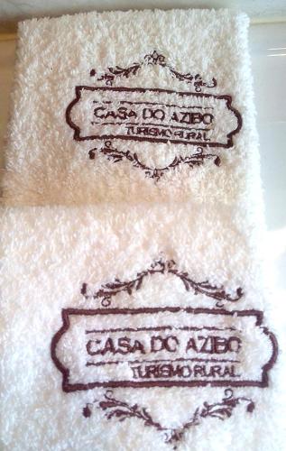 two white towels with black writing on them at Casa do Azibo in Santa Combinha