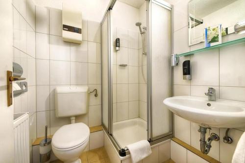 a bathroom with a toilet and a sink and a shower at Hotel Dortmund City in Dortmund