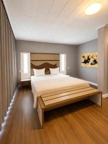 a bedroom with a large bed with a wooden headboard at Hotel Dortmund City in Dortmund