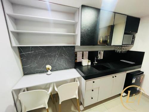 a kitchen with a white counter and white chairs at LM One Jardim Oceania in João Pessoa