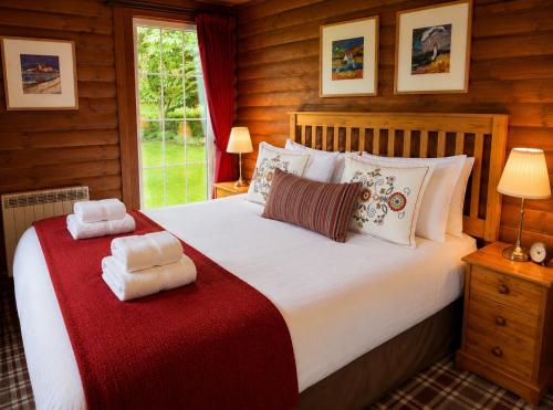 a bedroom with a large bed with a red blanket at Pucks Glen Lodges - Log Cabins in a wonderful natural environment in Dunoon