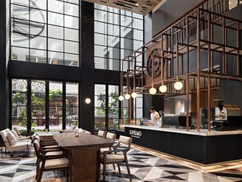 a restaurant with a table and chairs and windows at Mövenpick Hotel Jakarta City Centre in Jakarta