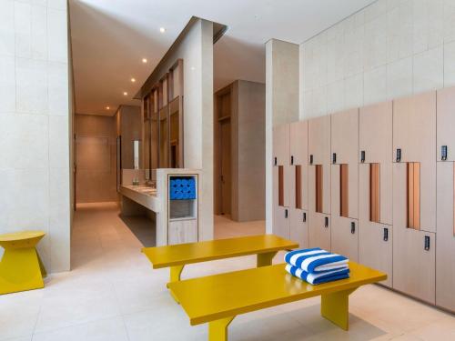 a locker room with yellow benches and white cabinets at Novotel Riyadh Sahafa in Riyadh