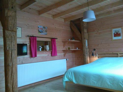 B&B De Luttikhoeve في Giethmen: غرفة نوم بجدران خشبية وسرير وتلفزيون