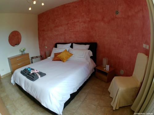 a bedroom with a large white bed and a chair at Locazione Turistica Spaccarotella Vista su Gualdo Cattaneo in Gualdo Cattaneo