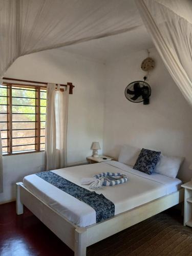 a bedroom with a white bed with a window at Gabsgate Resort Kilifi in Kilifi