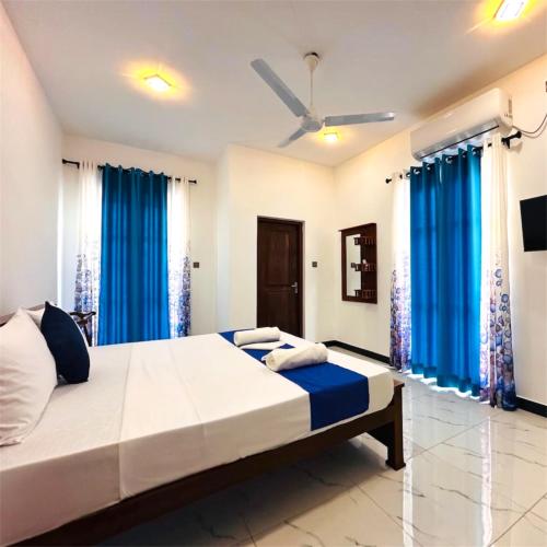 a bedroom with a large bed with blue curtains at New Aqua Glory in Negombo