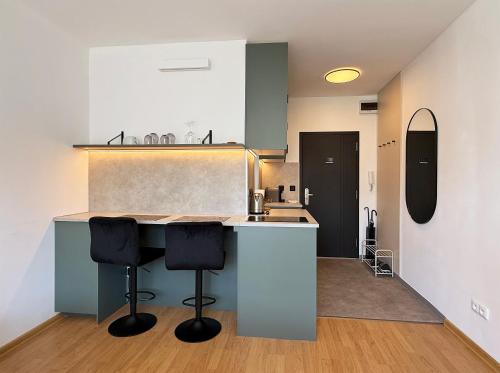 a kitchen with two bar stools at a counter at Cozy Emerald Studio Bratislava in Bratislava