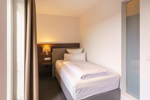 a small bedroom with a white bed in a room at Hotel DuDa Langenbruck 3-Sterne-Superior-Hotel an der A9 zwischen Ingolstadt und München in Langenbruck