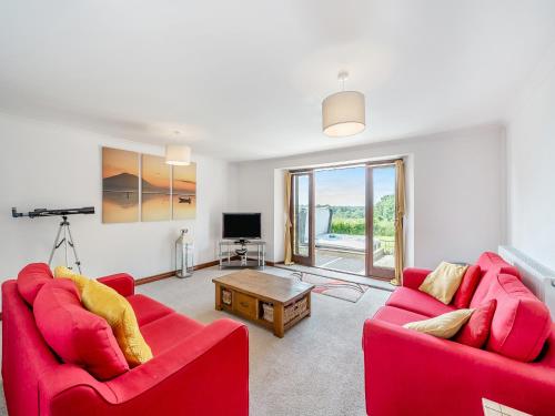 a living room with two red couches and a table at Holgates in Upottery