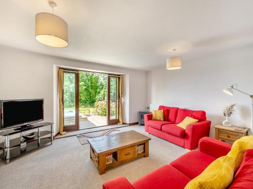 a living room with red couches and a tv at Holgates in Upottery