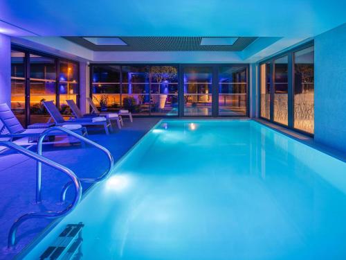 a swimming pool in a house with chairs and tables at Mercure Le Mans Batignolles - Hotel & Spa in Le Mans