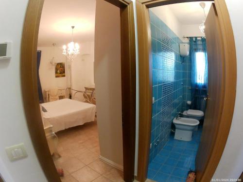 a blue tiled bathroom with a toilet and a bedroom at Locazione Turistica Spaccarotella Vista su Gualdo Cattaneo in Gualdo Cattaneo