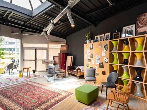 a living room with chairs and a green ottoman at Mercure Reims Parc Des Expositions in Reims